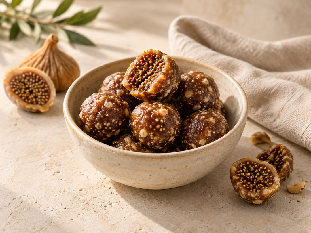Editorial illustration: A small bowl of round dried fig snack balls with a few cut pieces exposing dense fig seeds.