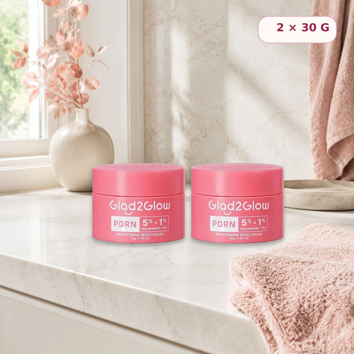 Two Glad2Glow PDRN moisturizer jars on a bright bathroom vanity
