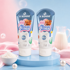 Two A BONNÉ Beauty Cheesy Thousand Milk Body Scrub tubes in a pastel blue and pink spa setting