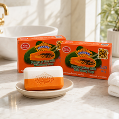 Two boxes and one two-colour bar of ASANTEE Papaya and Rice Milk with Honey Soap in a bright bathroom