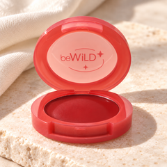beWiLD Fruity Balm, shade 01 Tomato, on a sunlit beauty vanity
