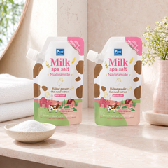 Two Yoko Milk Spa Salt Niacinamide 350 g body scrub pouches in a pink bathroom spa setting